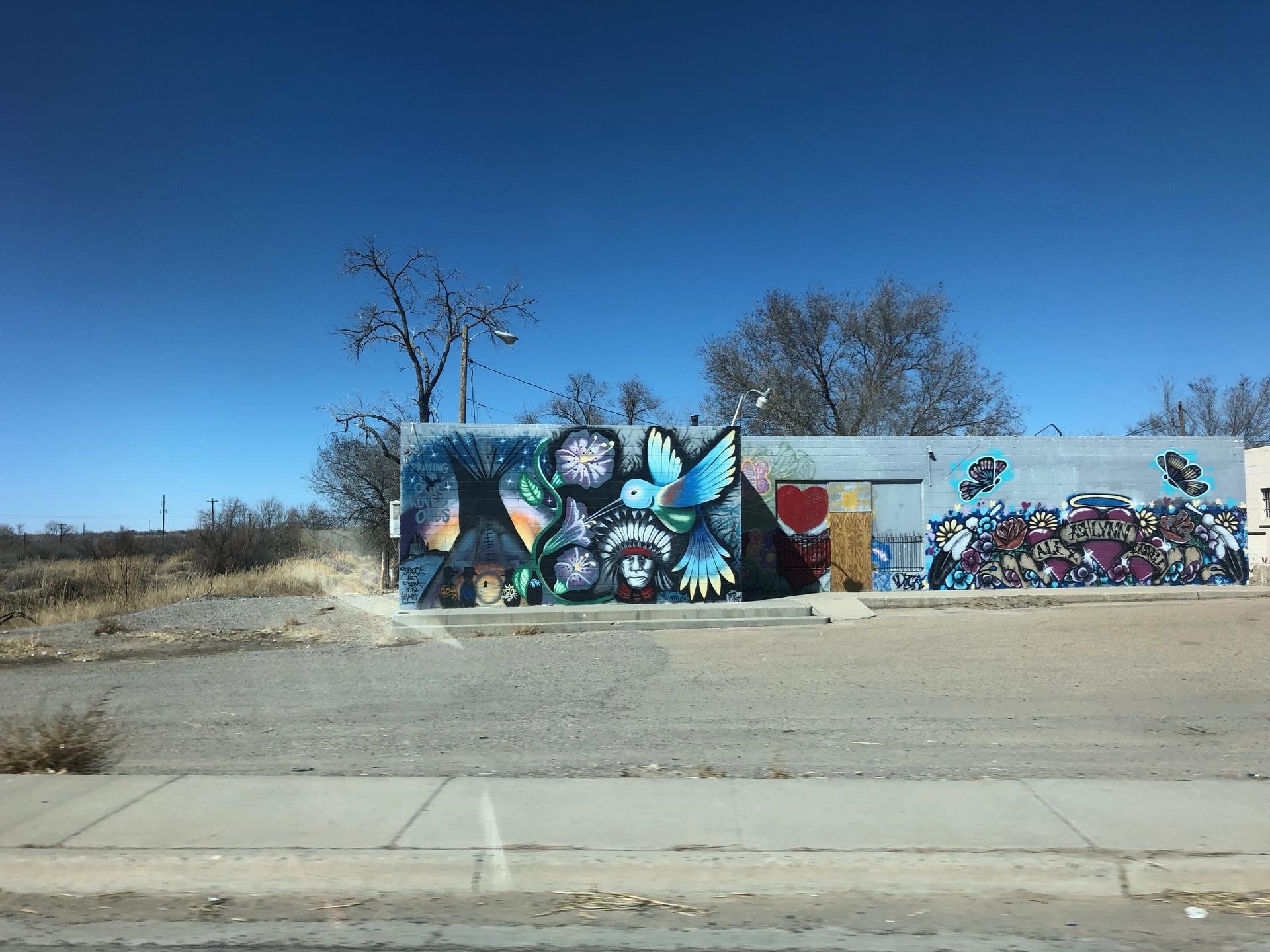 cinderblock building with a large graffiti hummingbird near Shiprock