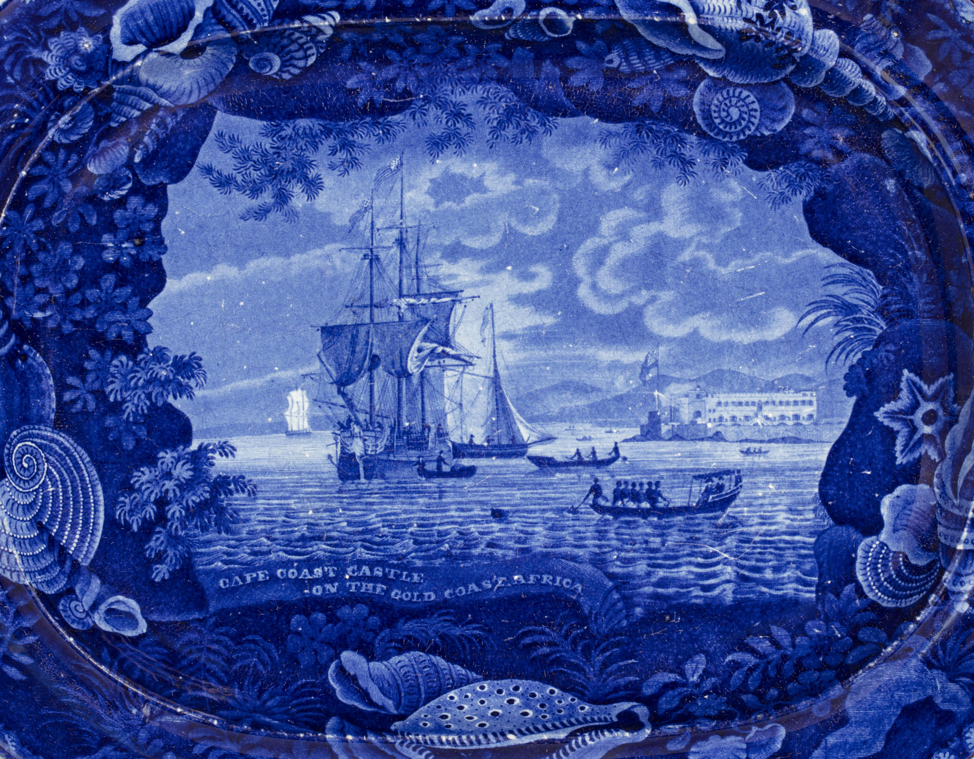 detail of the Cape Coast Castle platter, blue and white transferware depicting a slave ship with a shell border