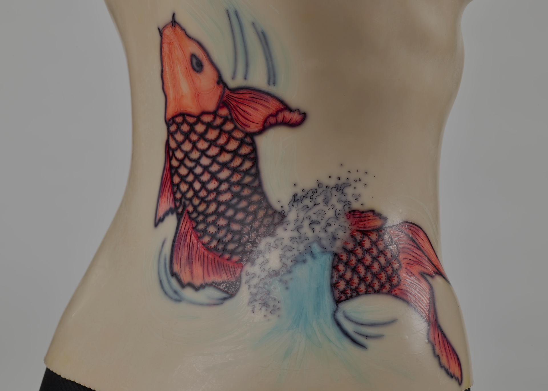 An off-white back brace is molded onto a black mannequin torso. The plastic brace attaches down the middle of the torso. A red koi design decorates the right side.